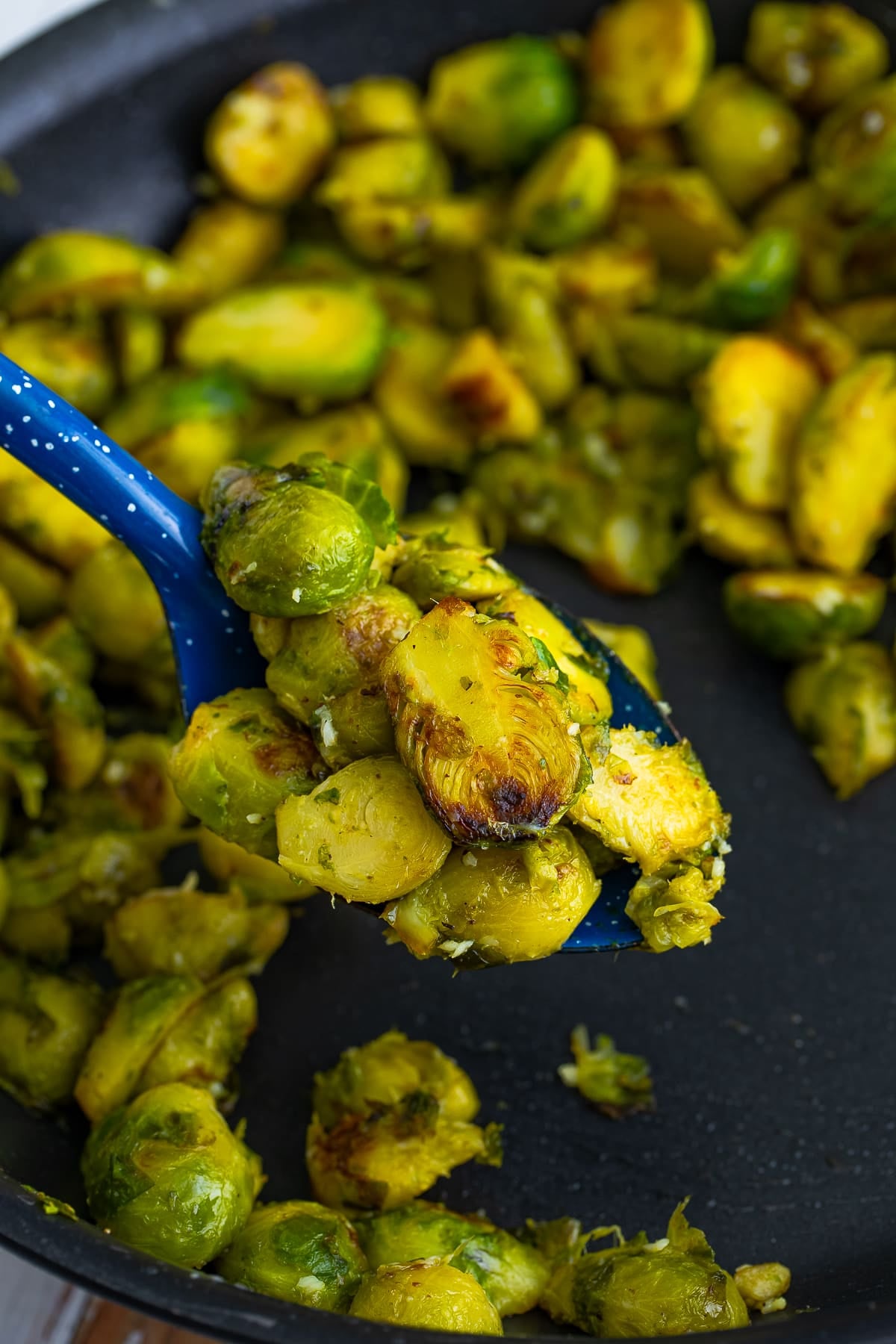 a serving spoon holding up a portion of Brussels Sprouts in a Pan over skillet