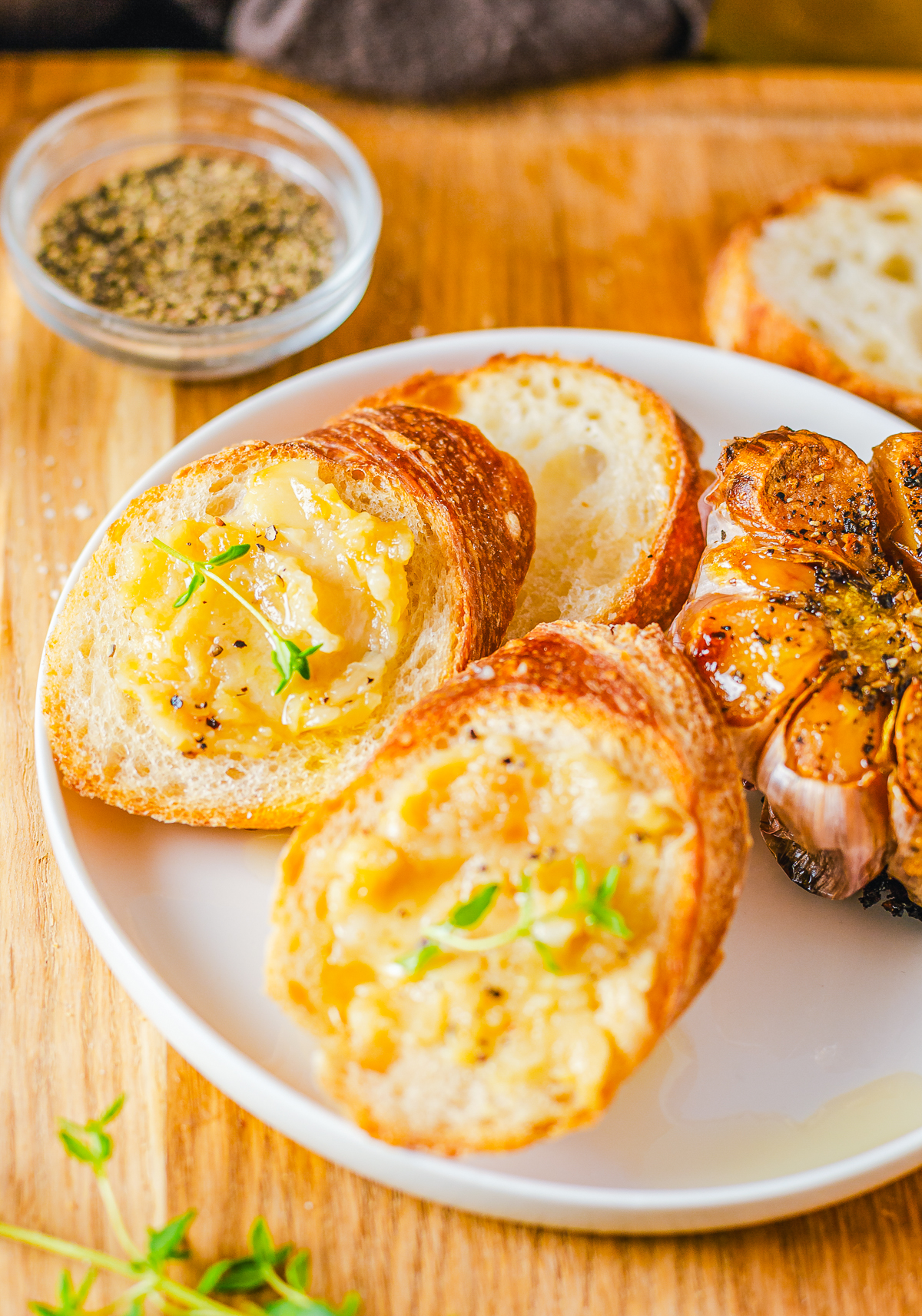Roast Garlic Spread on slices of bread with a whole garlic on the side.