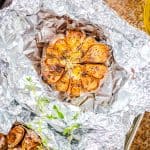 A head of roasted garlic with golden caramelized cloves resting on foil