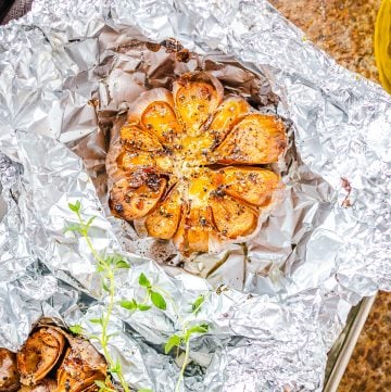 A head of roasted garlic with golden caramelized cloves resting on foil