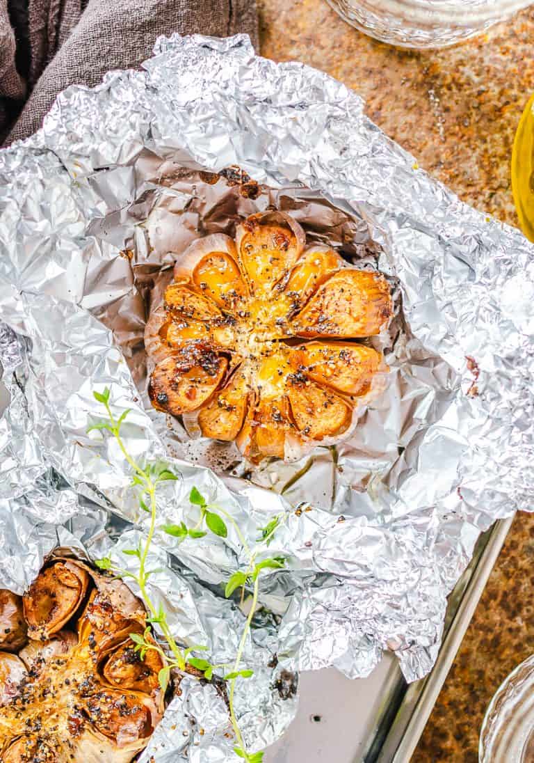 A head of roasted garlic with golden caramelized cloves resting on foil