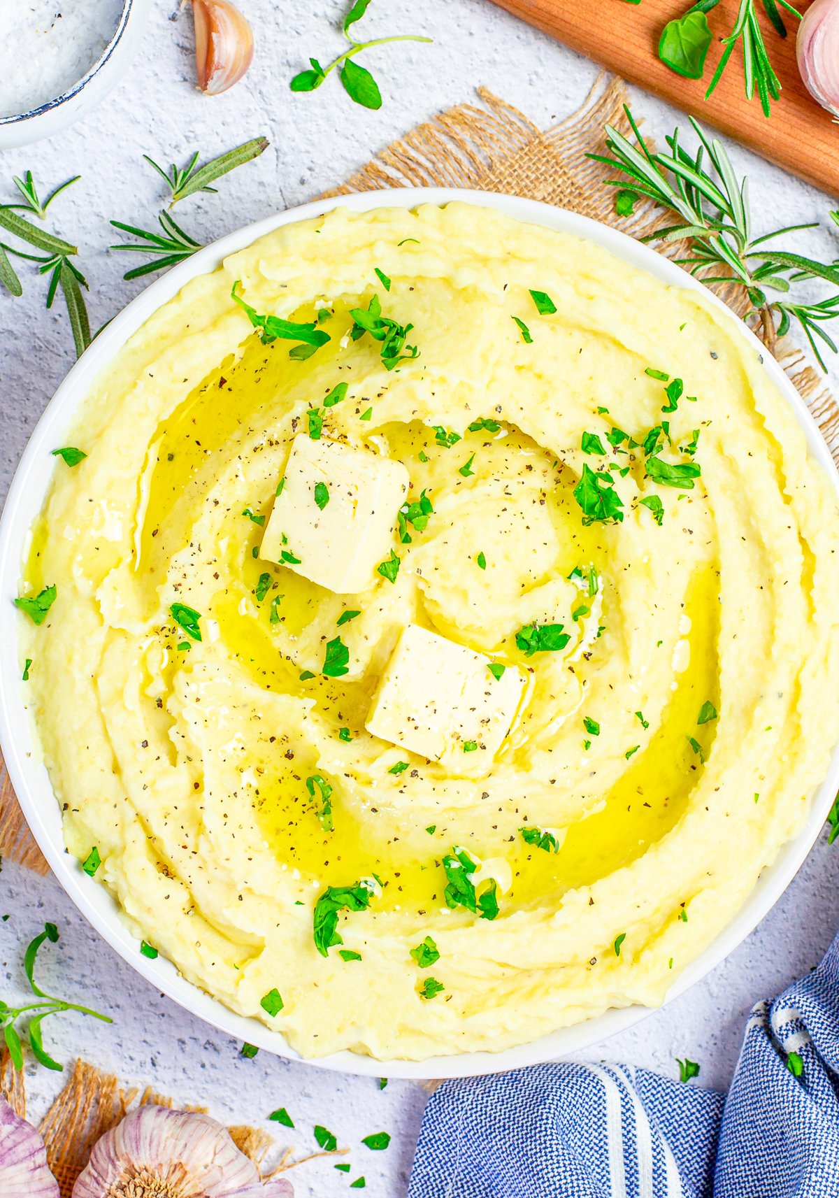 Overhead image of Creamy Mashed Potatoes in seerving bowl with butter and parsley.