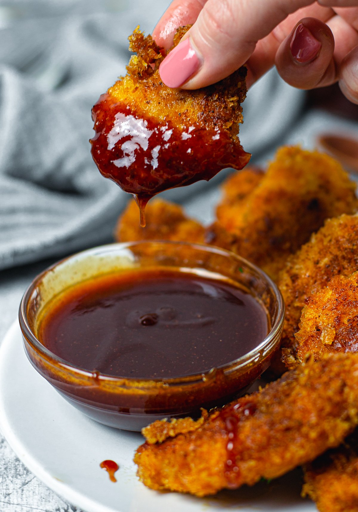 Chicken being dipped in BBQ Sauce
