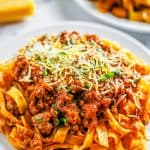 A pot of thick, hearty meat sauce served over pasta with parmesan.