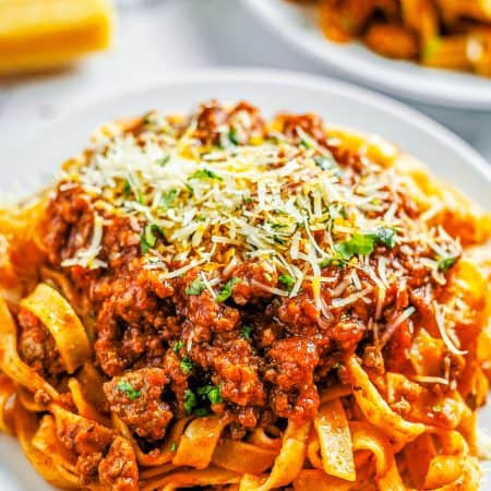 A pot of thick, hearty meat sauce served over pasta with parmesan.