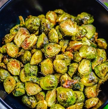 Easy Oven Roasted Brussel Sprouts Recipe served in a wooden bowl, halved sprouts roasted golden brown on the edges with crispy outer leaves and tender centers, ready to serve as a side dish.