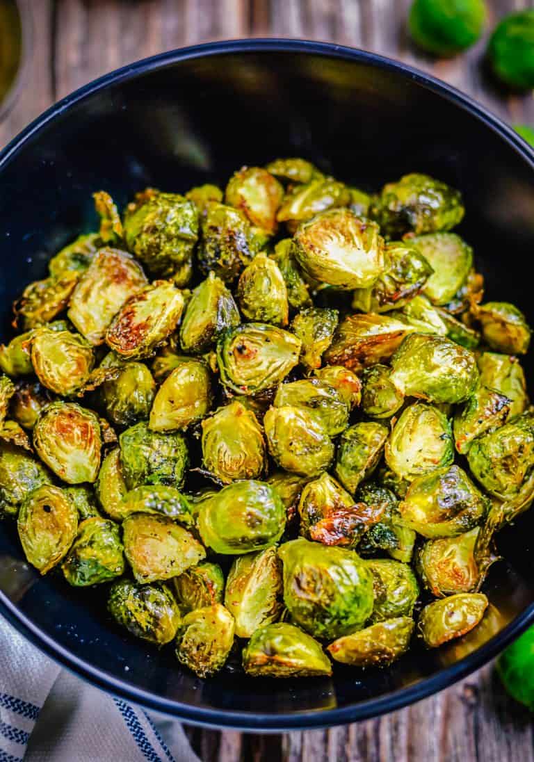 Easy Oven Roasted Brussel Sprouts Recipe served in a wooden bowl, halved sprouts roasted golden brown on the edges with crispy outer leaves and tender centers, ready to serve as a side dish.