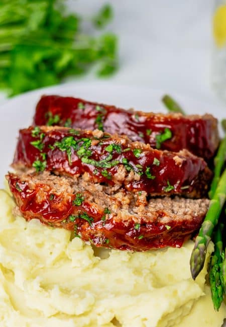 Three slices of Easy Meatloaf over mashed potatoes.