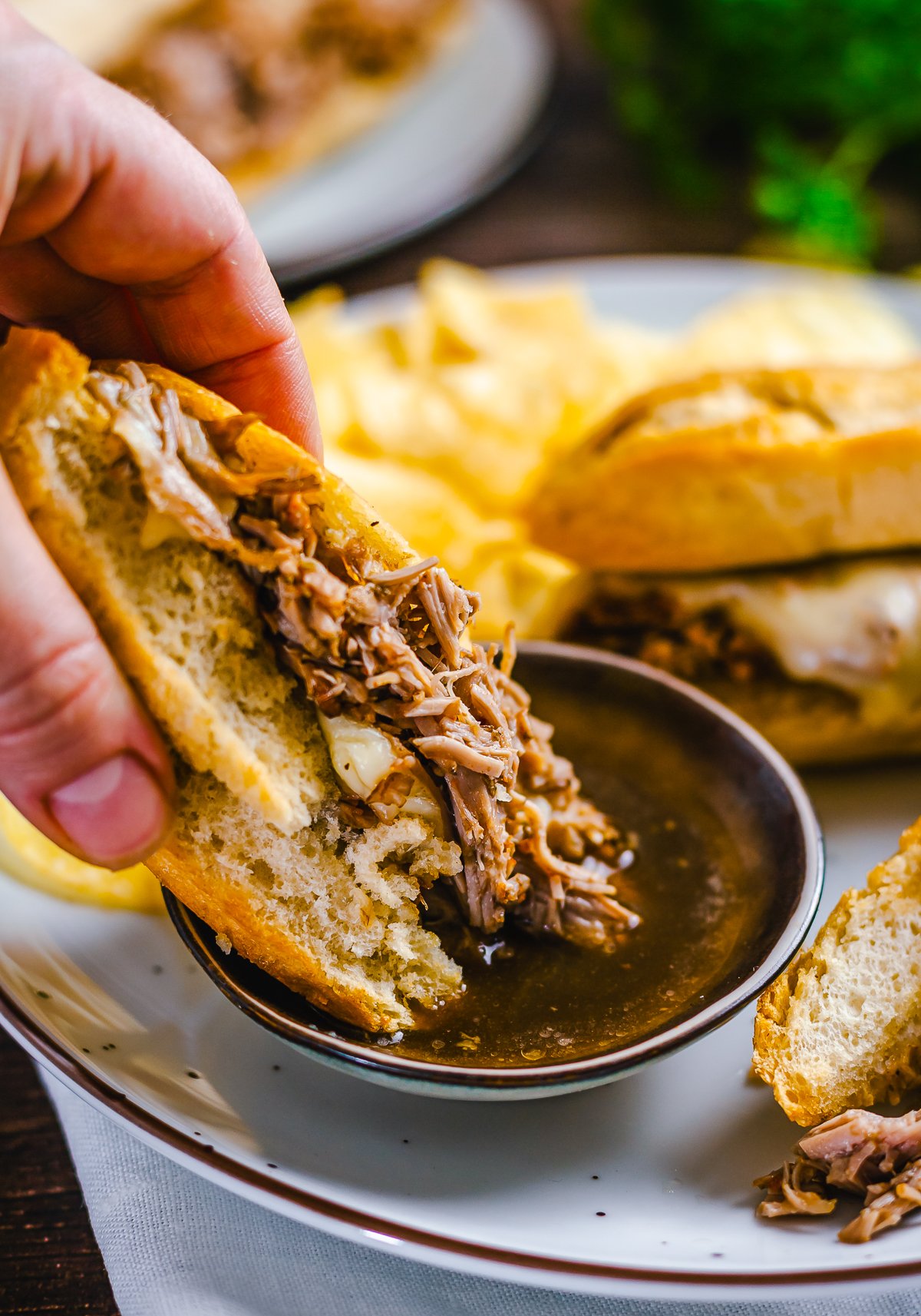 Sandwich being dipped into au jus.