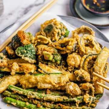 Tempura Vegetables on plate with dipping sauce in back.