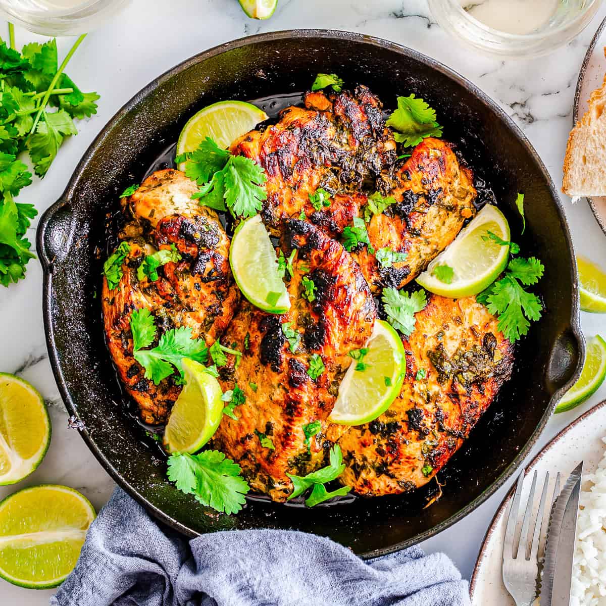 Cilantro lime chicken breasts in a cast iron skillet garnished with lime and cilantro.