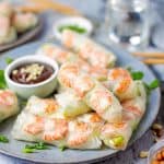 A plate of fresh spring rolls filled with shrimp, lettuce, and noodles served with hoisin peanut dipping sauce.