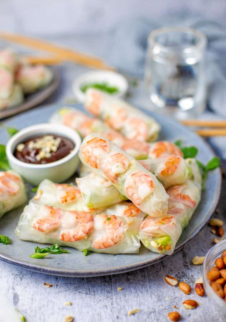 A plate of fresh spring rolls filled with shrimp, lettuce, and noodles served with hoisin peanut dipping sauce.