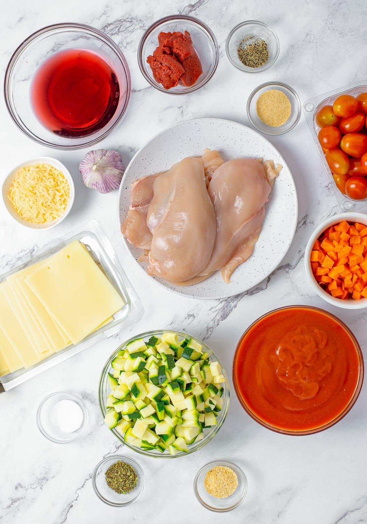 Overhead photo of ingredients needed to make Healthy Chicken Parmesan on a grey marble tabletop