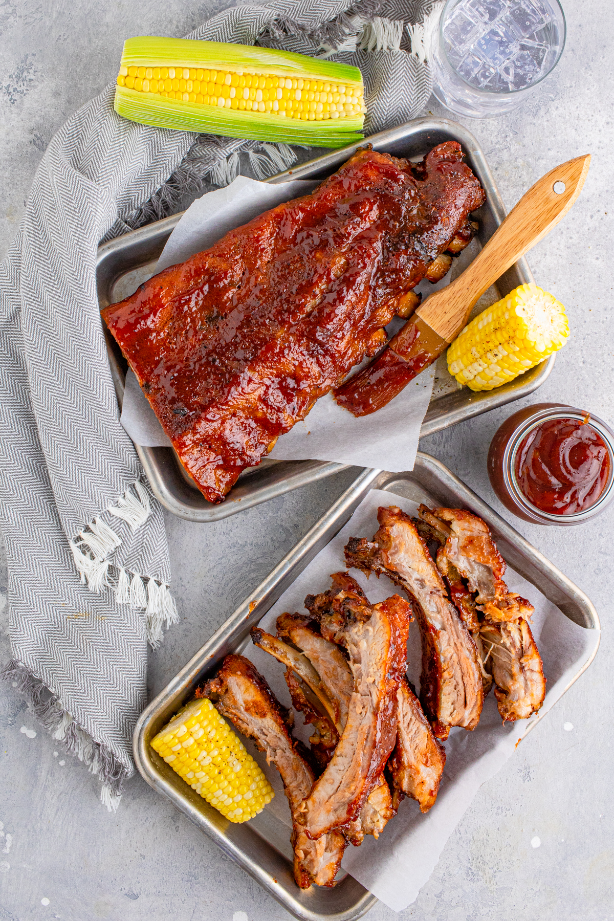 Overhead of BBQ Rib Recipe on metal platters with corn and bbq sauce