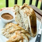 Sliced slow cooker Cajun turkey breast on a white plate with a bowl of seasoning.