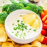 Two chips in a bowl of Roasted Garlic Cream Cheese Dip.