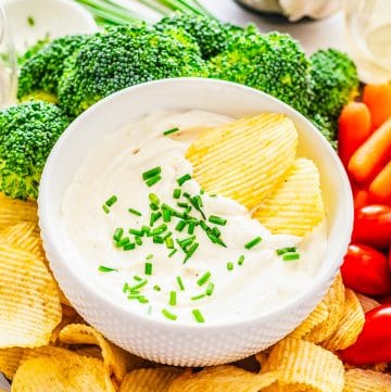 Two chips in a bowl of Roasted Garlic Cream Cheese Dip.