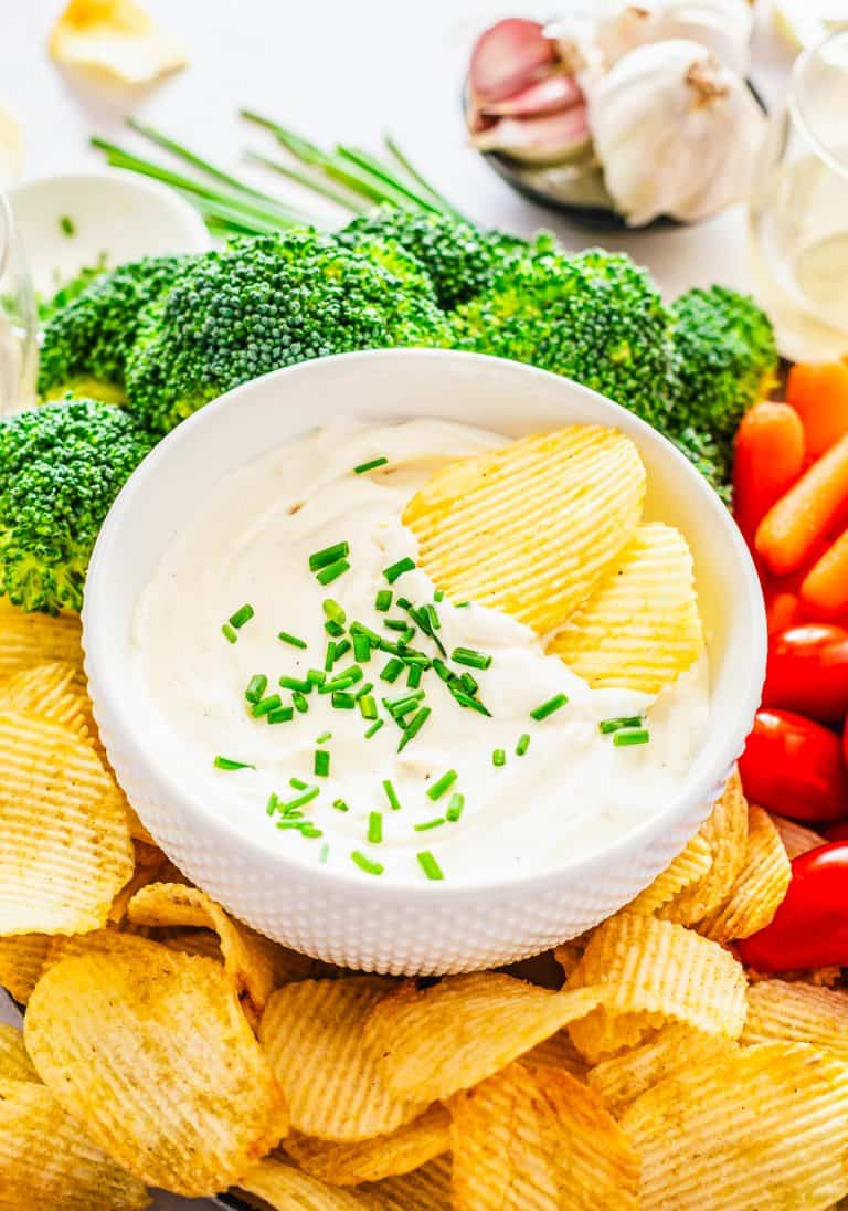Two chips in a bowl of Roasted Garlic Cream Cheese Dip.