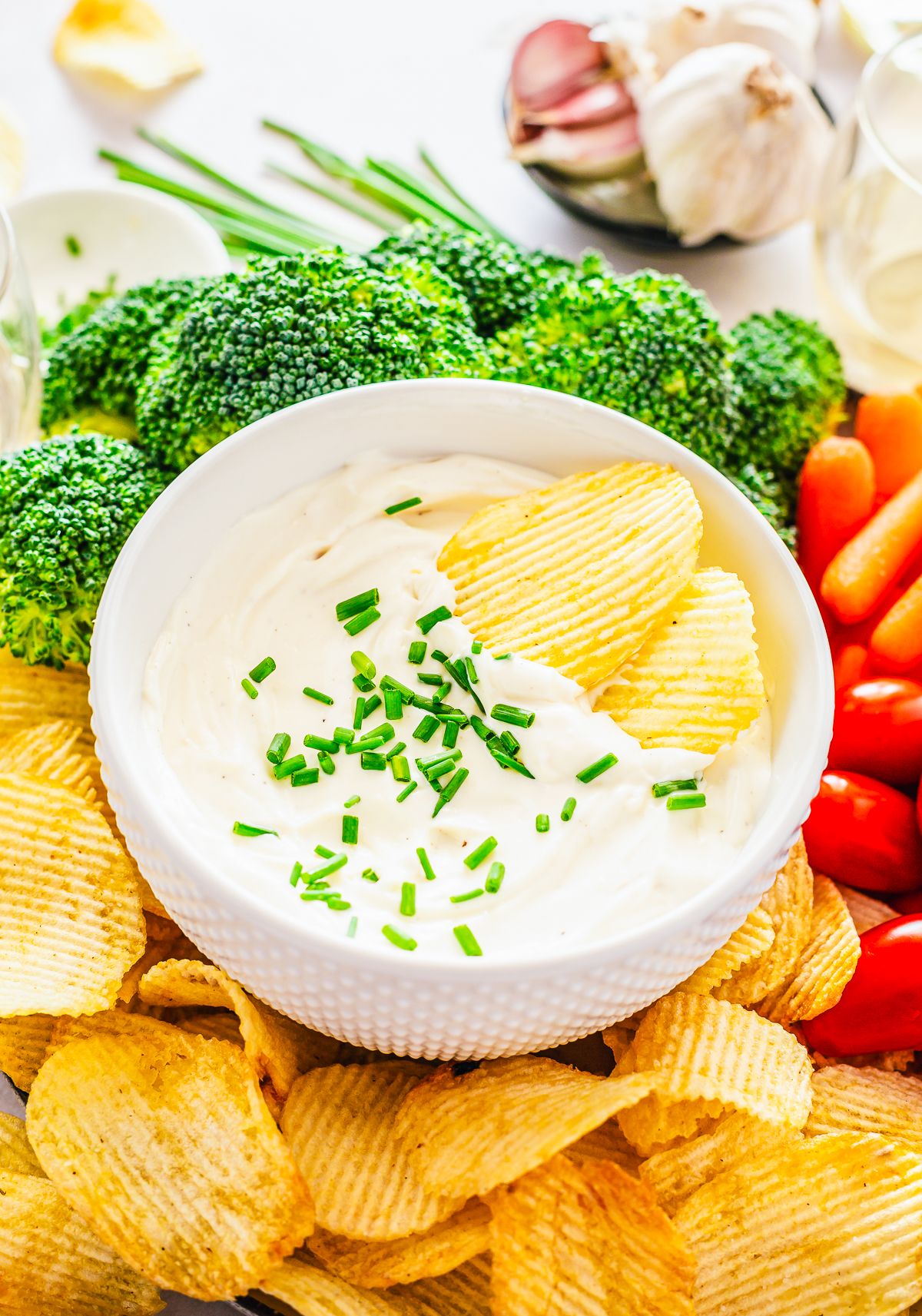 Two chips in a bowl of Roasted Garlic Cream Cheese Dip.