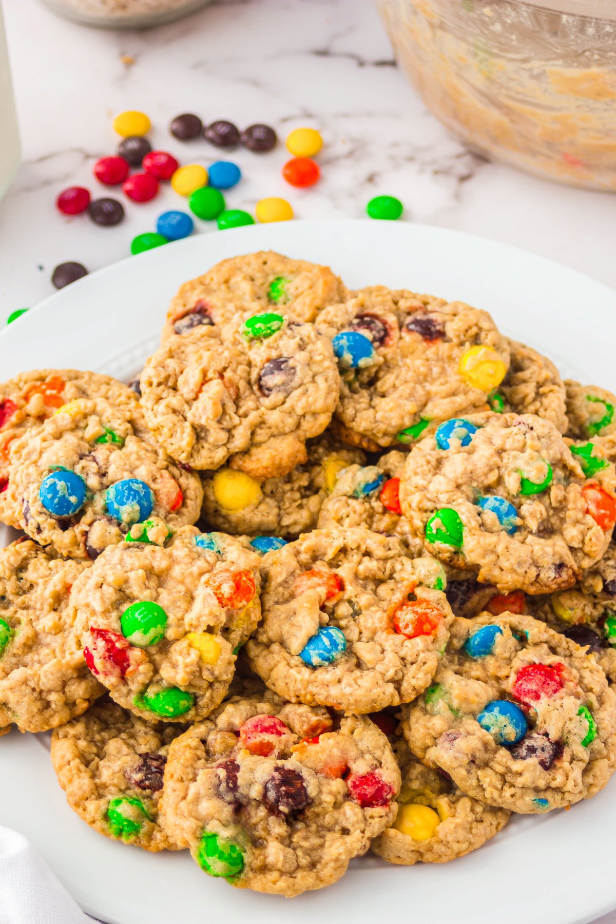 M&M Oatmeal Cookies stacked on white plalte.