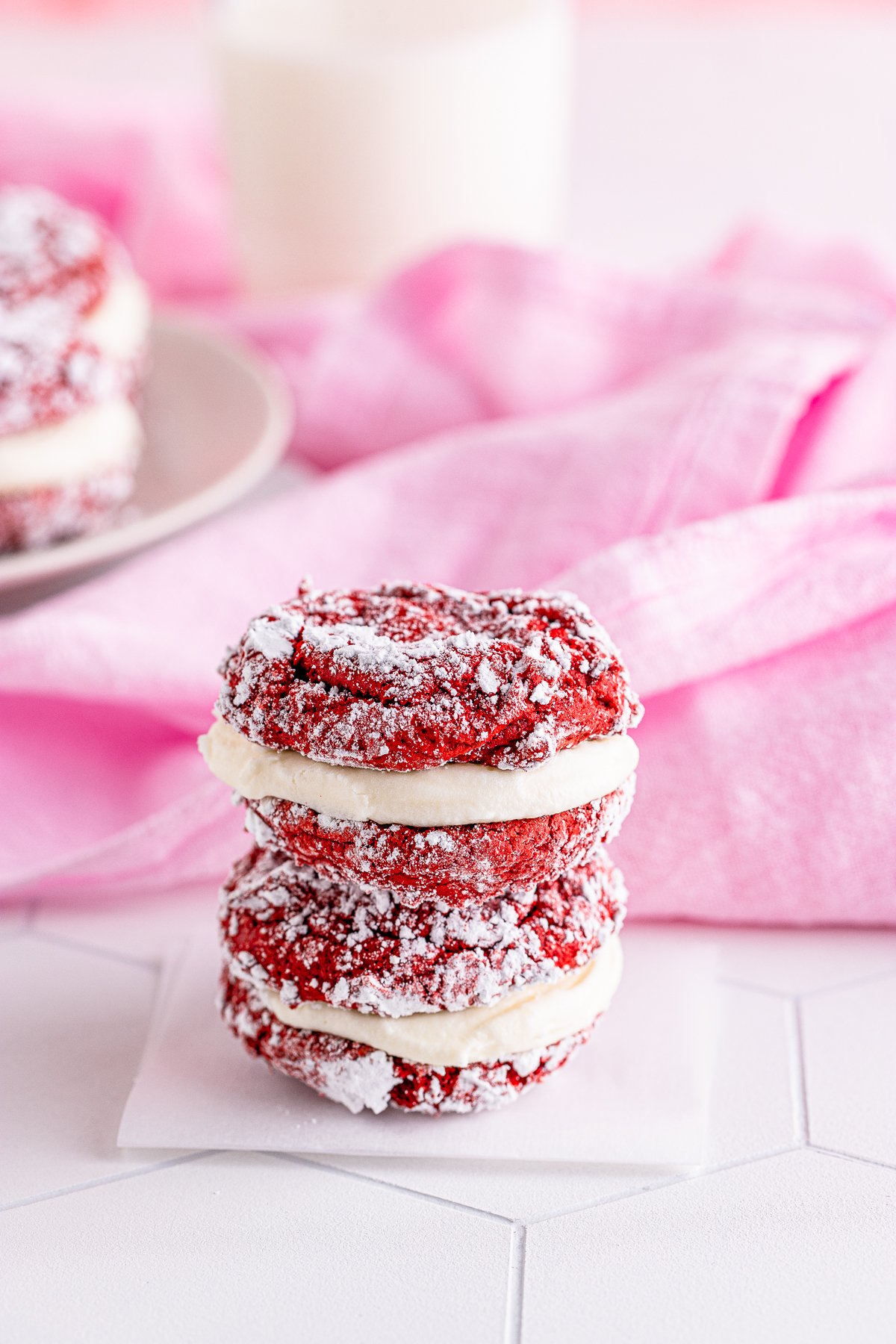 Two stacked Red Velvet Sandwich Cookies on a square of parchment paper.