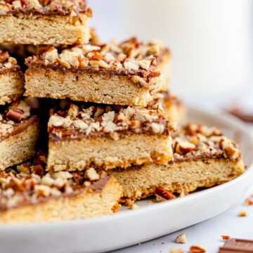 Side view of stacked Chocolate Toffee Pecan Bars on plate.