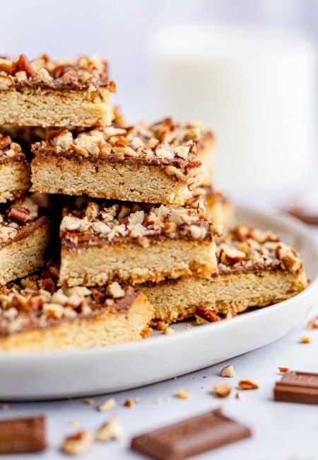 Side view of stacked Chocolate Toffee Pecan Bars on plate.
