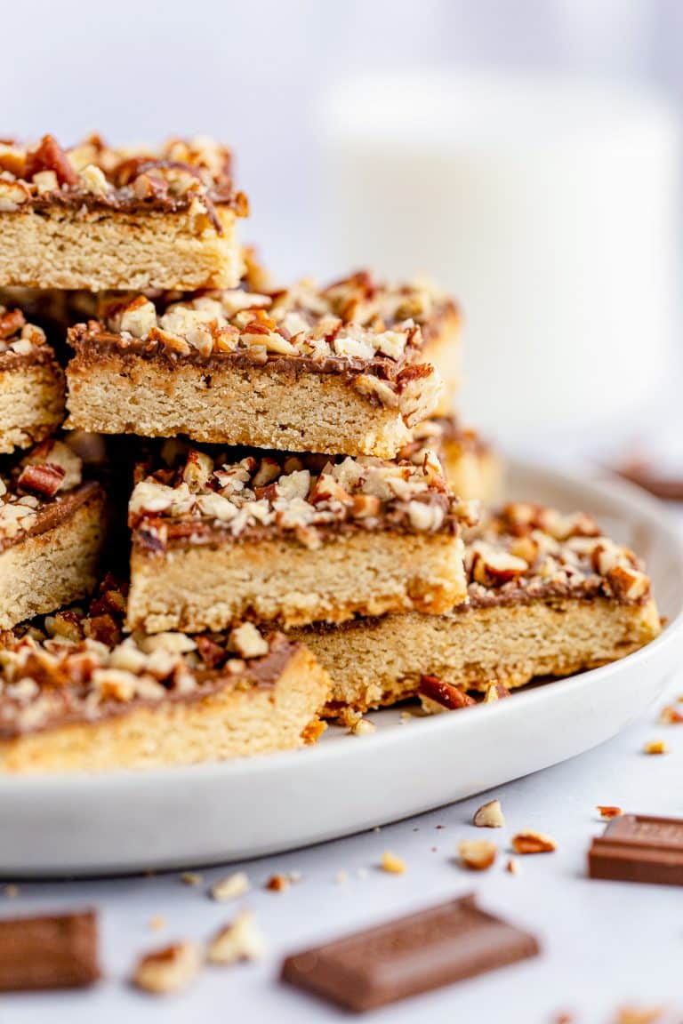 Side view of stacked Chocolate Toffee Pecan Bars on plate.