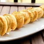 Golden baked goat cheese pinwheels lined up on a white oval platter.