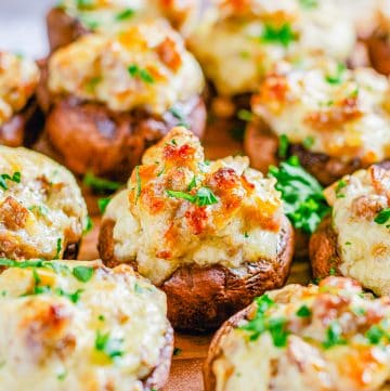 Sausage stuffed mushrooms with cream cheese baked golden brown and garnished with parsley.