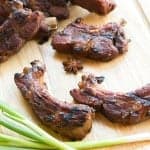 Glazed Chinese ribs on a cutting board with fresh scallions and star anise