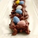 A close-up of a chocolate peanut butter pretzel bird nest topped with speckled candy mini eggs.
