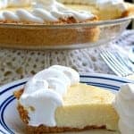 A slice of creamy key lime pie topped with whipped cream on a blue-rimmed plate.