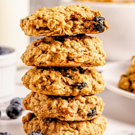 Stacked Blueberry Oatmeal Cookies on top of one another with blueberries at bottom.