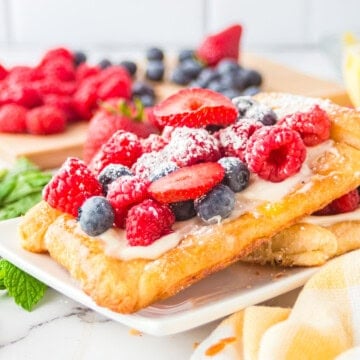 Berry tarts topped with fresh strawberries, blueberries, and raspberries and dusted with powdered sugar.