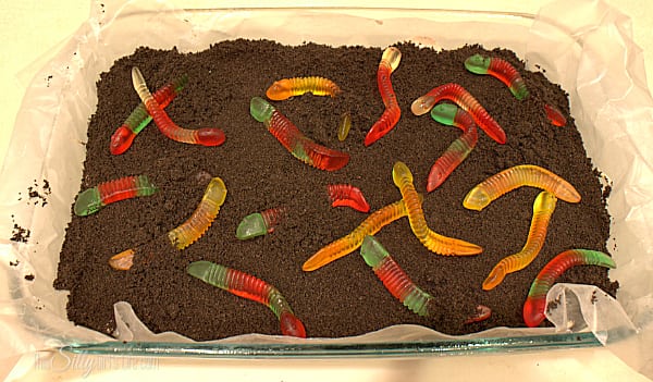 Top the whole thing with the remaining cookie crumbs. Place in freezer for at least 4 hours or until completely set. To serve, top with gummi worms and cut into bars, enjoy!