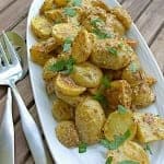 French Potato Salad piled on a white platter coated in whole grain mustard vinaigrette and fresh parsley.