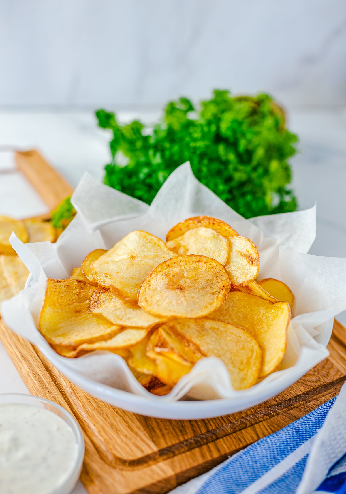 Finished Homemade Potato Chips in basket with parchment paper.