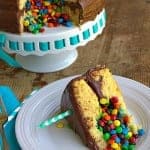 A slice cut from a Pinata Cake with mini chocolate candies spilling out of the hidden center.