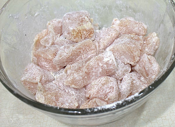 Start by preparing the chicken, dice chicken breasts into 1/2 inch to 1 inch pieces. Place in a bowl and add the cornstarch, flour, onion powder, garlic powder and pepper. Toss until all the chicken pieces are coated. 