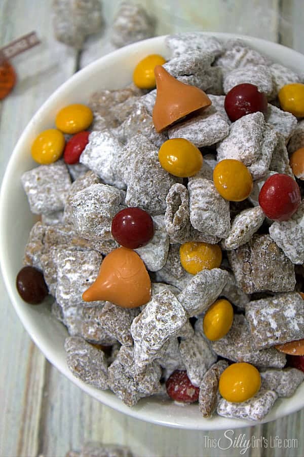 Finished Halloween muddy buddies tossed with fall candies in a white bowl.