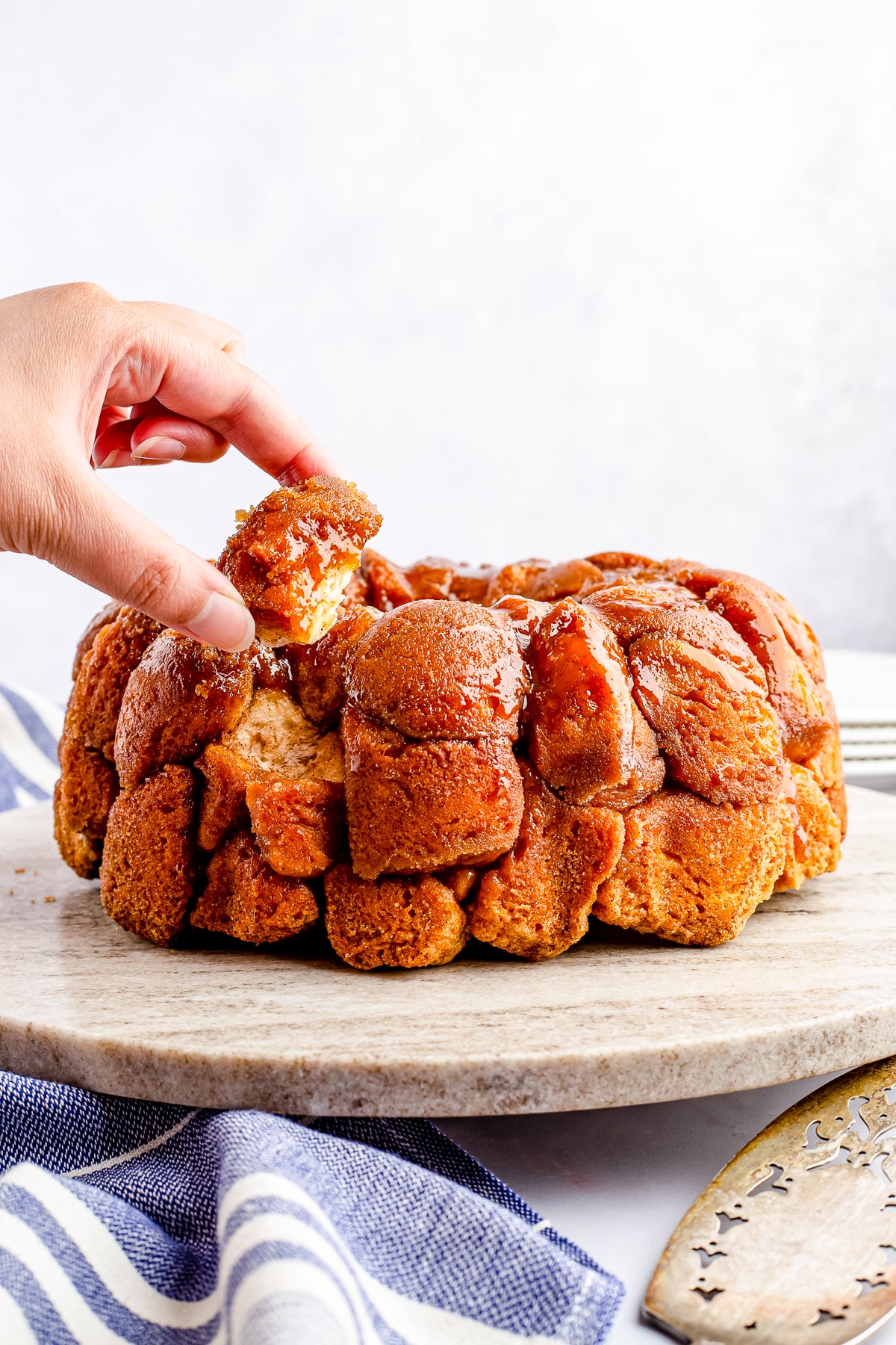 Hand pulling a piece from the Monkey Bread on platter.