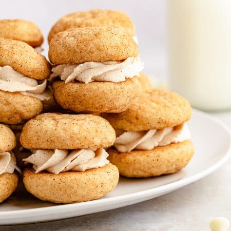 Close up side view of Snickerdoodle Sandwich Cookies stacked on white plate.