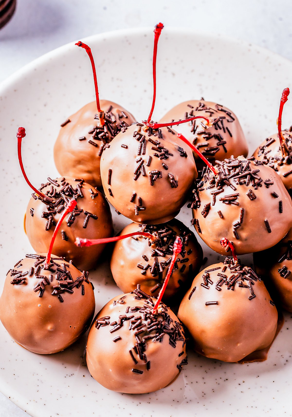 Close up of Chocolate Cherry Oreo Truffles stacked on white plate.
