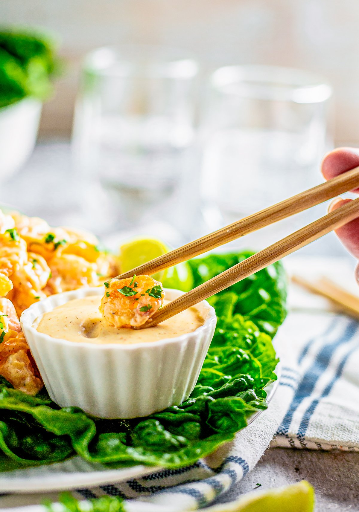 Chopsticks dipping one shrimp into dipping sauce.