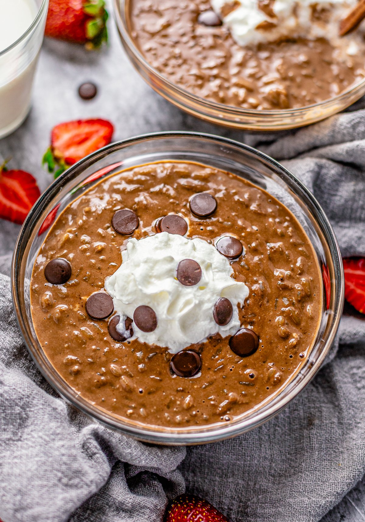 Two bowls of Chocolate Rice Pudding garnished with whipped cream and chocolate chips.