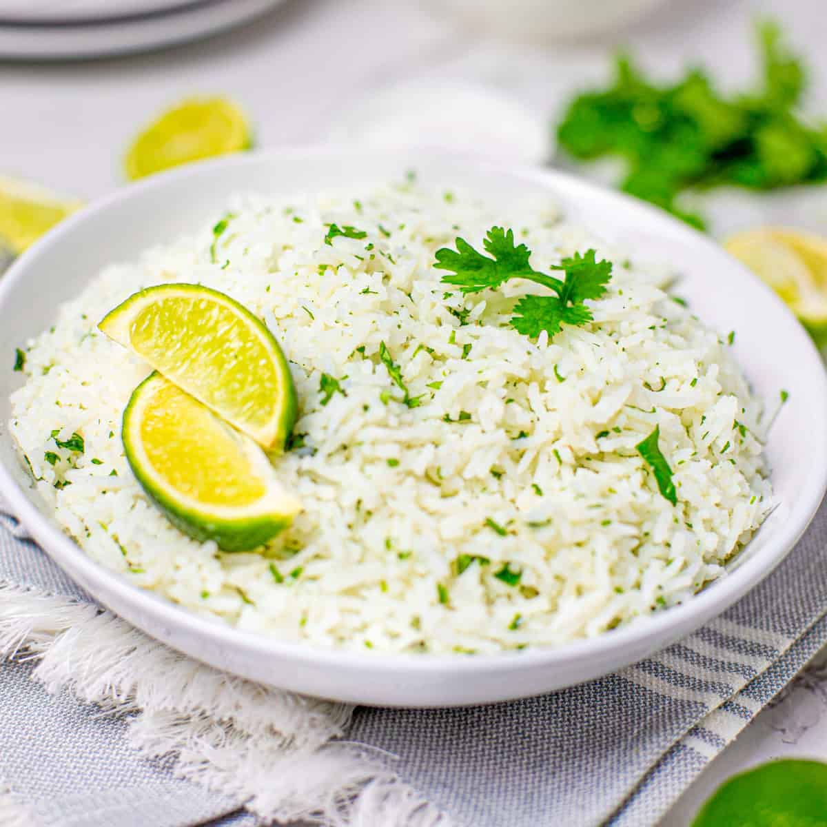 A white bowl of fluffy cilantro lime rice topped with a lime wedge and fresh cilantro