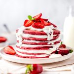 Square image of stacked pancakes showing cream cheese filling and strawberries.