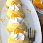 Individual Orange Creamsicle Pie servings topped with whipped cream and orange slices on a white platter.